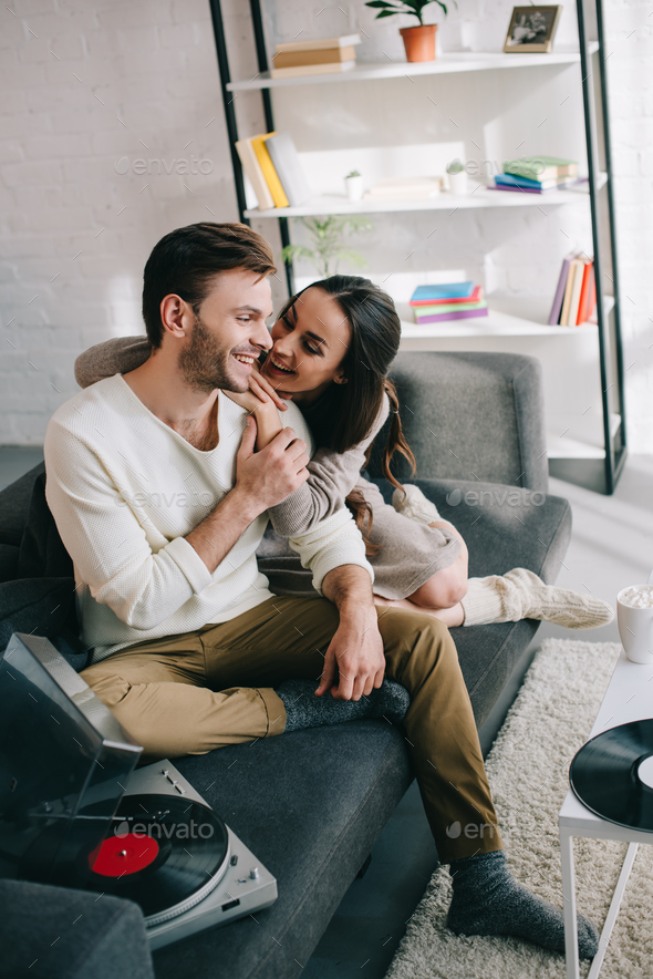 beautiful young couple listening music with vinyl record player and