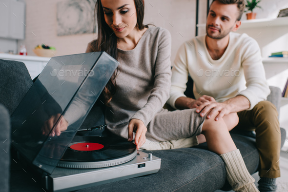 beautiful young couple listening music with vinyl phonograph at home