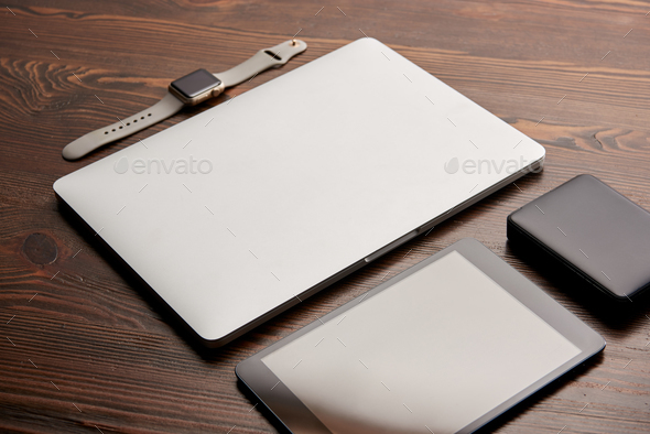close-up shot of laptop with digital tablet, smart watch and portable hdd on wooden table