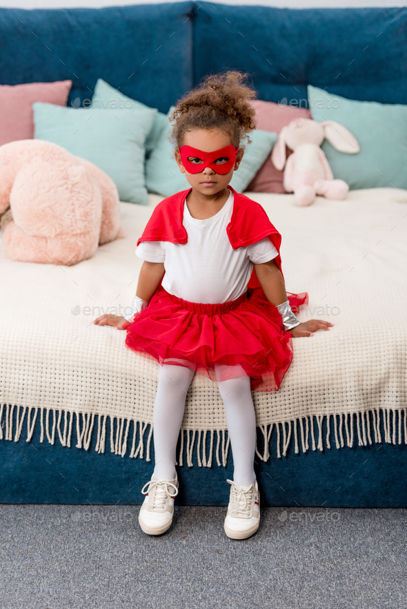 Cute little african american child in red superhero costume and mask