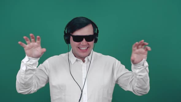 A man in glasses and headphones is dancing in slow motion.