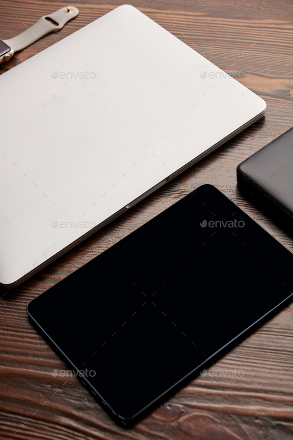 close-up shot of laptop with tablet, smart watch and portable hdd on wooden table