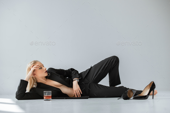 Stylish Half Naked Woman In Black Trendy Suit Lying On Grey With Glass Of Whiskey Stock Photo By