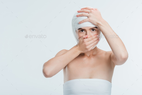 woman with white bandages on head closing mouth with hand isolated on white