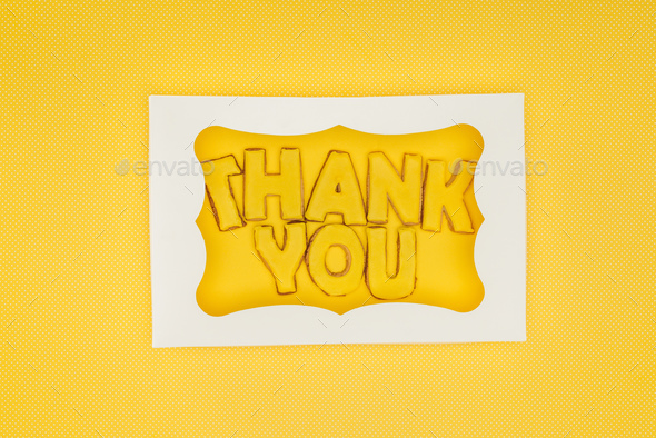 square-shaped cake in box with thank you lettering isolated on yellow background