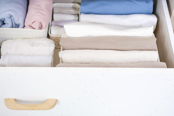 Clothes folded in a box in a chest of drawers close-up, space organization concept.