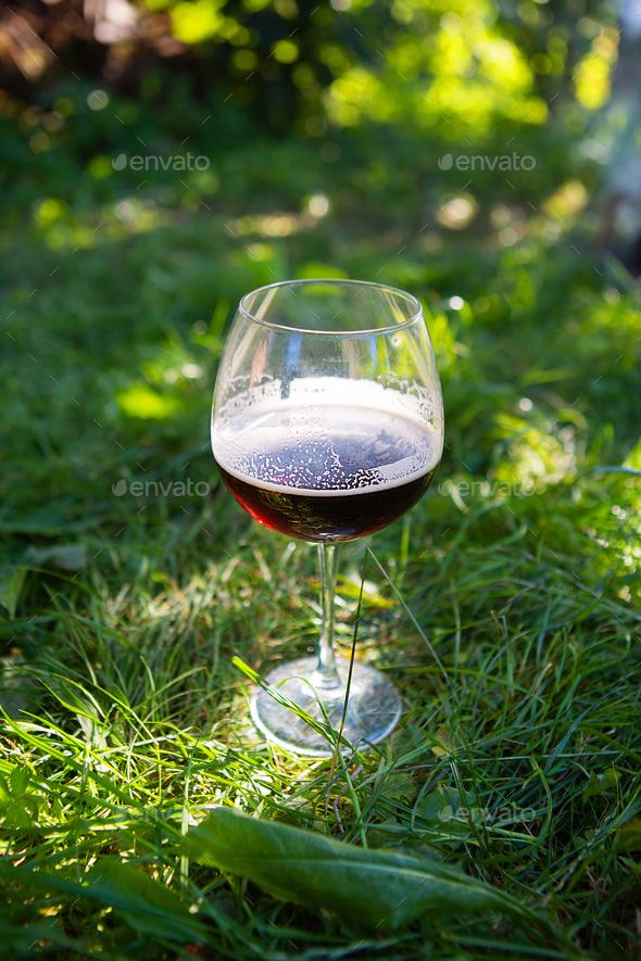 Glass of beer on green grass in public park, beautiful sunlight. The concept of outdoor recreation
