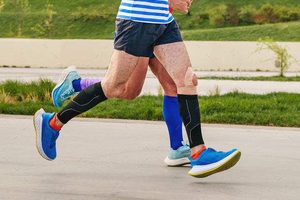 legs two male runners in compression socks and sleeves run marathon distance