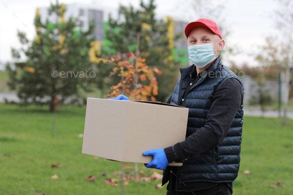 Delivery Man in Yellow Uniform Medical Face Mask and Gloves Holds