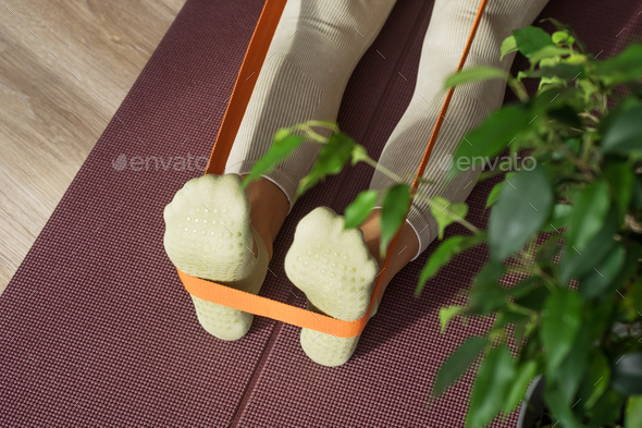 Trainer doing leg stretching exercises with orange fitness rubber bands. Fitness trainer doing