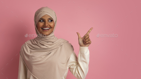 Nice Offer. Smiling Arab Woman In Hijab Pointing Aside At Copy Space