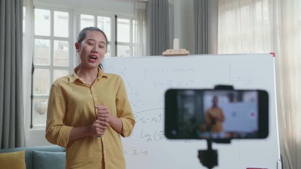 Asian Female Teacher With Marker Pen Shoots Video By Smartphone Camera While Teaching Math At Home alt