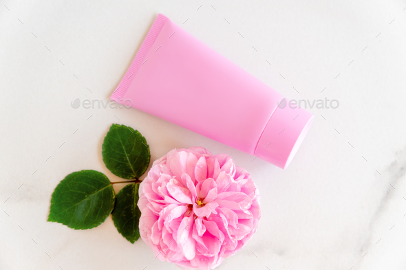 pink tube with rose face or body cream or scrub decorated with pink core flowers. Skin care co