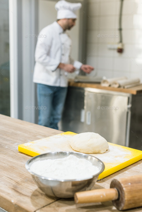 adult baker in chefs uniform preparing dough at counter Stock Photo by