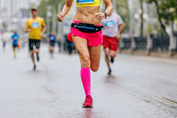 female runner in compression socks running ahead group athletes