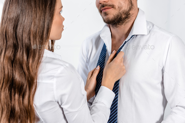 cropped image of girlfriend tying boyfriend tie in morning at home, social role concept