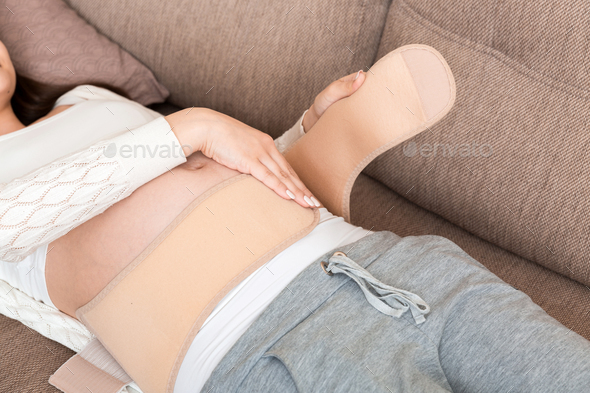 Pregnant womanlying on sofa in abdominal support bandage