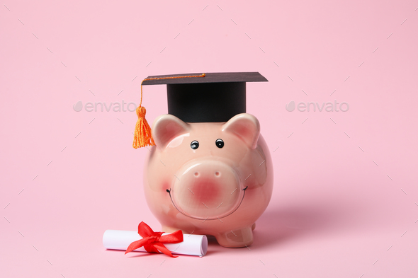 Piggy bank with graduation hat and degree scroll on pink background