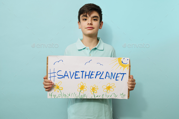 Young activist boy holds a sign that says save the planet.