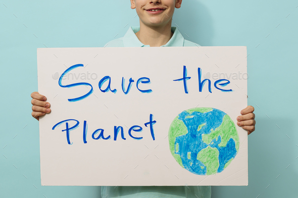 Young activist boy holds a sign that says save the planet.