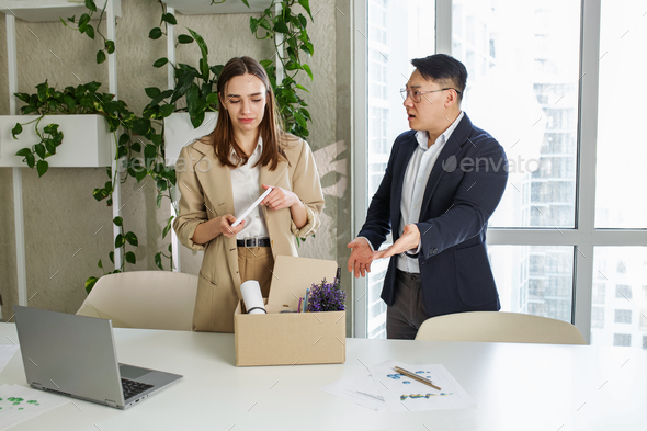 Employee layoff dismissal. Angry asian boss firing upset female employee in modern office.