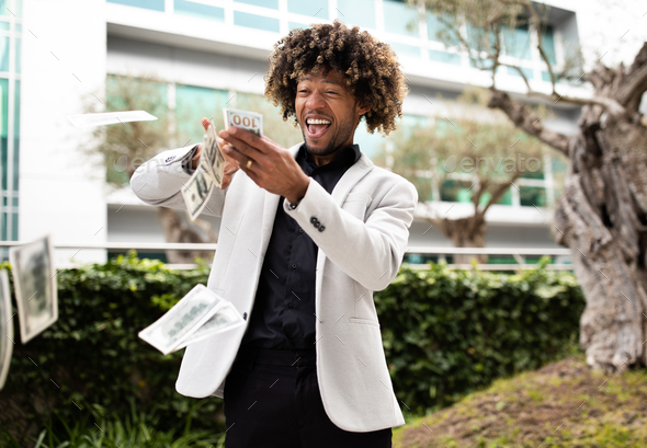 Overjoyed black middle aged businessman throwing money away showing his wealthiness, standing
