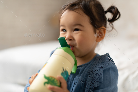 Toddler girl drinking water from the baby bottle Stock Photo