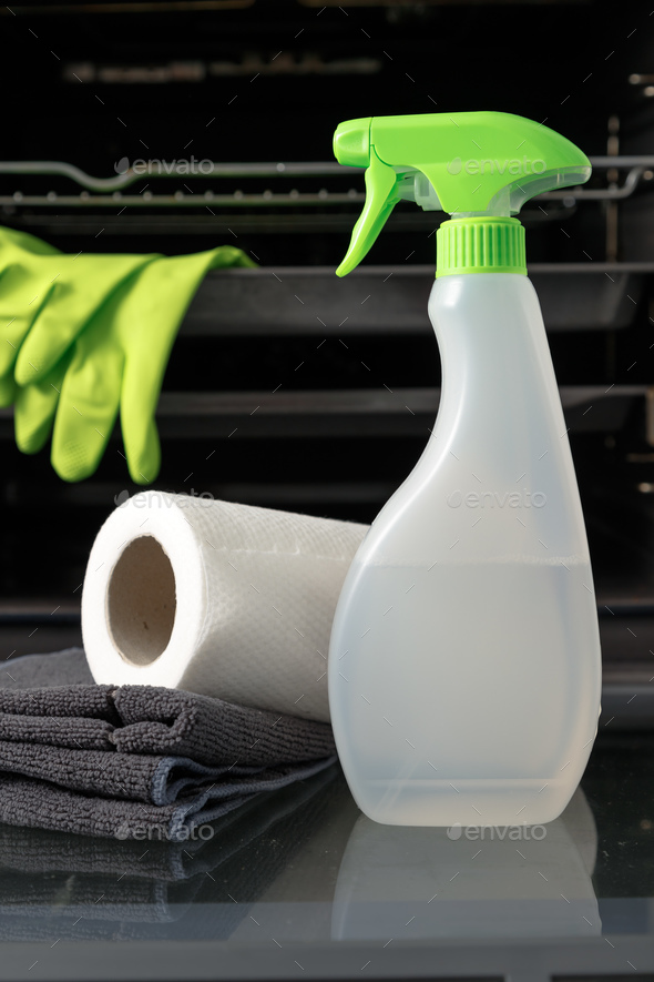 Oven cleaner kit on open door. Bottle with ecological health-friendly detergent, wipes and gloves