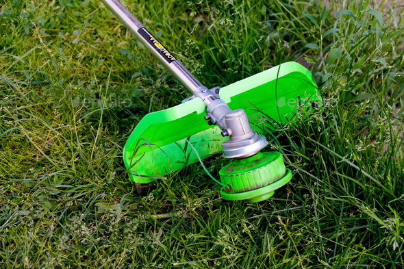 grass trimmer. A man mowing the grass. Outdoor view of a lawn trimmer mower cutting grass in a blurr