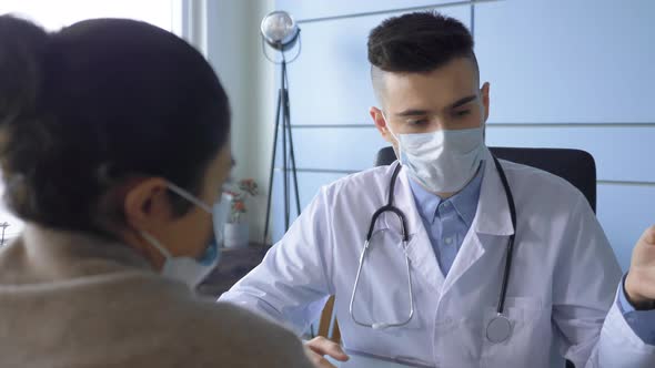 Young Indian Woman Patient Talks to Her Male Doctor In Doctor's Office. alt