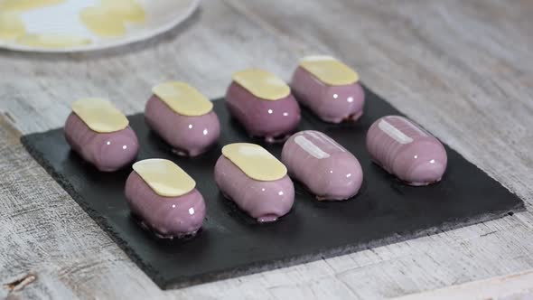 Preparing modern, french desserts - mousse with purple mirror glaze. Decorate french mousse cakes	 alt