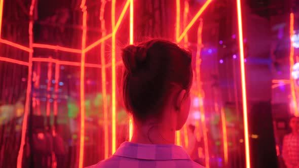 Back View Woman Looking Around at Exhibition or Museum with Colorful Red Light