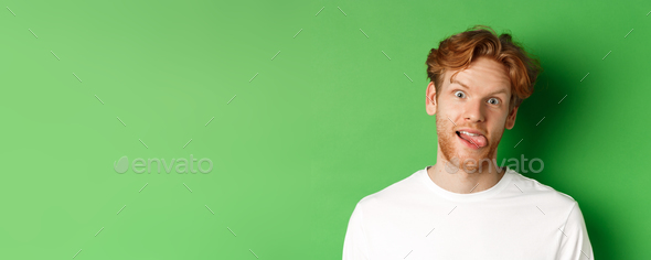 Emotions and fashion concept. Close up of funny redhead man showing silly faces, sticking tongue