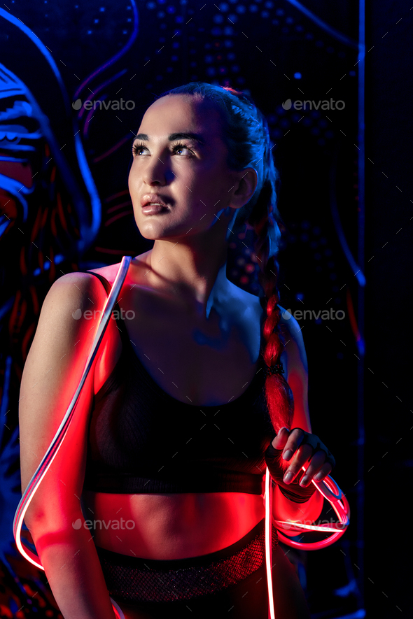 A young woman in fashionable youth club clothes in neon light.Red,purple,blue neon lights.Nightlife