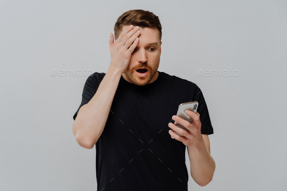 Impressed guy reading unexpected news in social media on smartphone with amazed expression