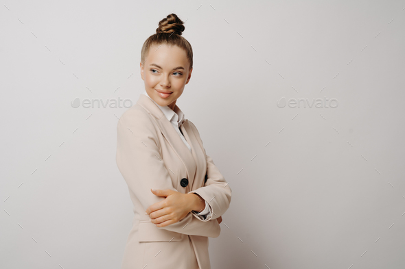 Office manager in beige suit with crossed arms standing on grey background - Stock Photo - Images