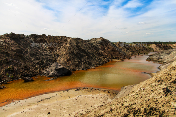 Yellow-orange toxic waste in water in sandpit