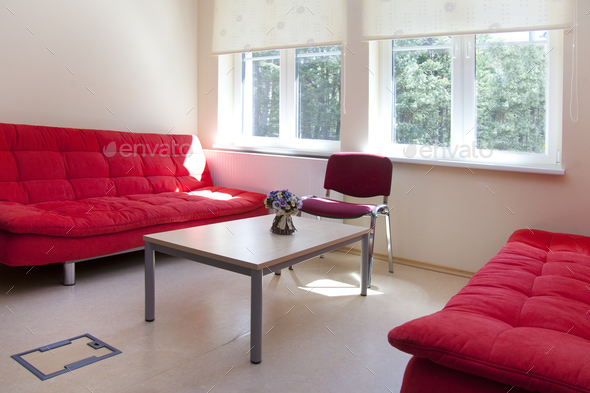 A staff room in a school, two red sofas and a table.