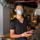 A man working in a restaurant, wearing a face mask, by an open kitchen, holding a digital tablet. - PhotoDune Item for Sale