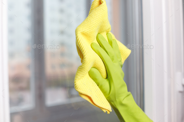 Hand in Green Glove Wiping Window with Microfiber Rag. Professional Cleaning Service