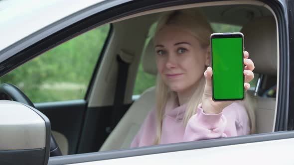 Woman scratching a phone in her hands while sitting in a car alt