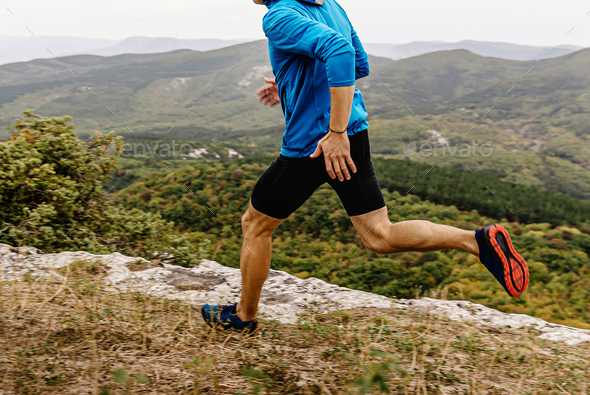 male runner in windbreaker and tights running along precipice, man jogger athlete run mountain trail - Stock Photo - Images