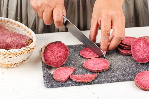Woman Slice Cut Japanese Purple Sweet Potato with Knife in the Kitchen