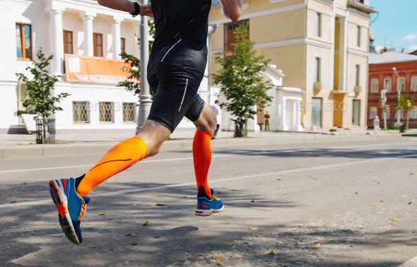 male runner in compression socks running street summer marathon race, endurance sports