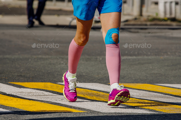 legs female runner in pink compression socks running pedestrian crossing