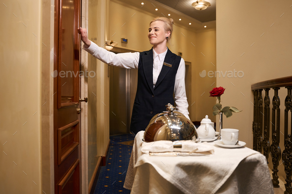Pleasant waitress knocking on the door of the hotel room