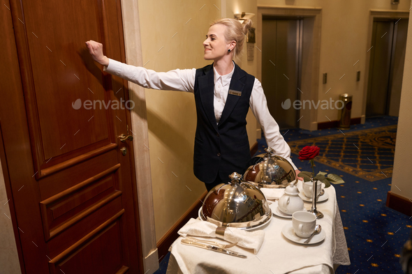 Waitress in uniform knocks on the door of hotel room
