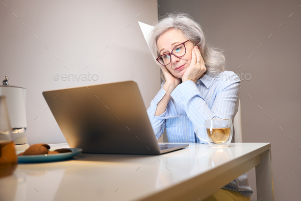 Melancholic lady settled down with a laptop at kitchen table