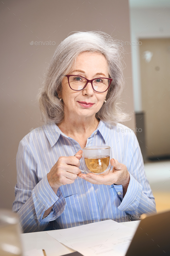 Sophisticated lady settled down with cup of tea at kitchen table
