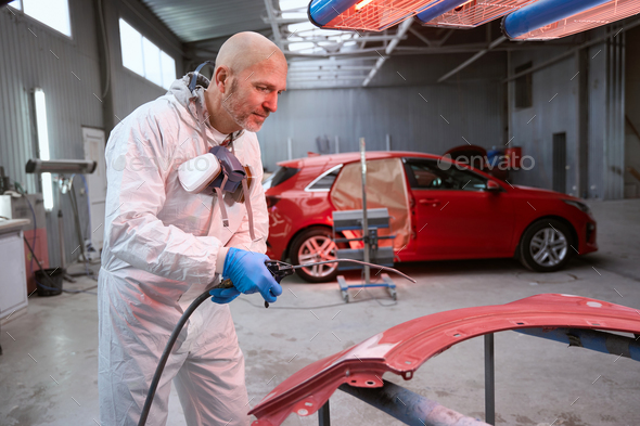 Optimistic male in work overalls picks up paint for car